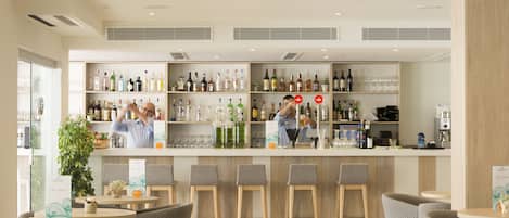 A modern bar area with shelves of various liquor bottles, a bar counter, and several stools.