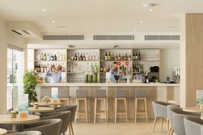 A modern bar area with shelves of various liquor bottles, a bar counter, and several stools. - Hotel HSM Linda Playa (Calvia)