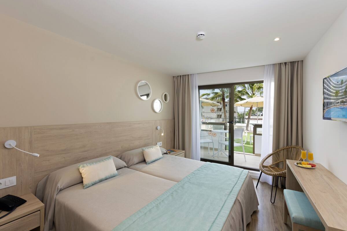 A hotel room with a large bed, a desk, and a view of the outdoor area.
