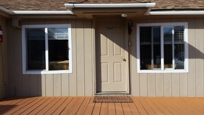 Una casa con fachada color beige, una puerta principal y dos ventanas con contraventanas.