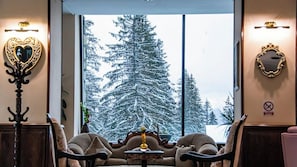 A room with a large window, a heart-shaped mirror, a chandelier, and a fireplace.