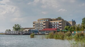 Un hotel de varios pisos con un edificio de techo rojo junto a una masa de agua.