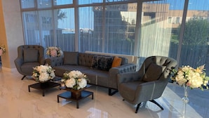 Una sala moderna con un sofá gris, dos sillones y una mesa de centro con arreglos florales.