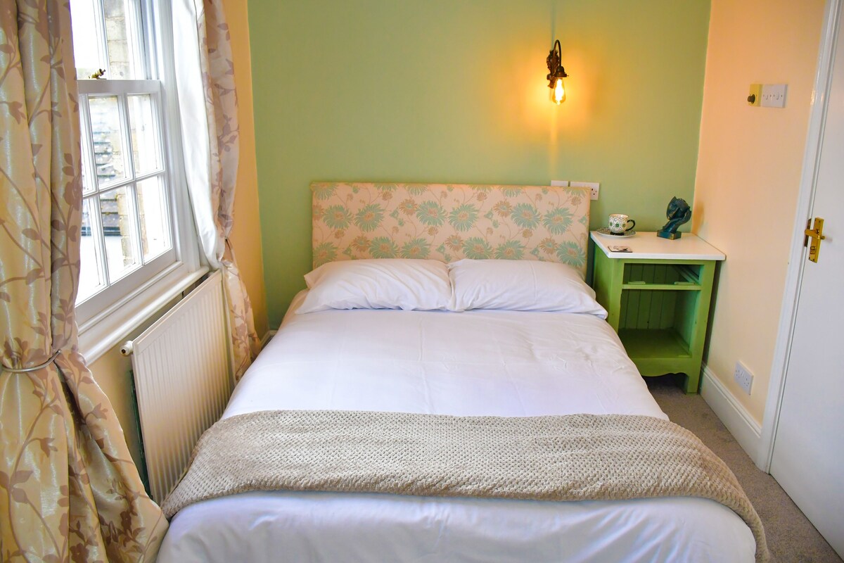 Ein Schlafzimmer mit einem Bett, einem Nachttisch, einer Wandleuchte und einer Heizung.