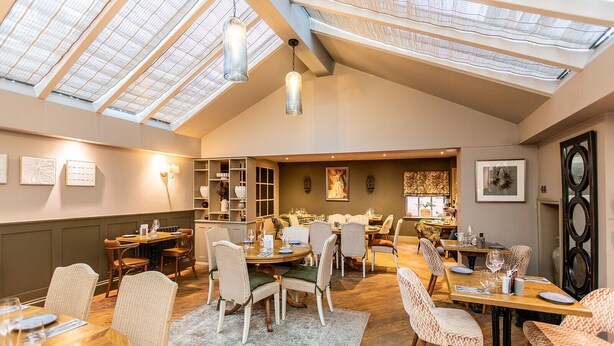 A dining area with high ceilings, skylights, and a variety of seating arrangements. - The Boot at Repton (Derby)