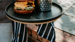 A person holding a tray with a sandwich, burger, and a cup of fries. - The Boot at Repton (Derby)