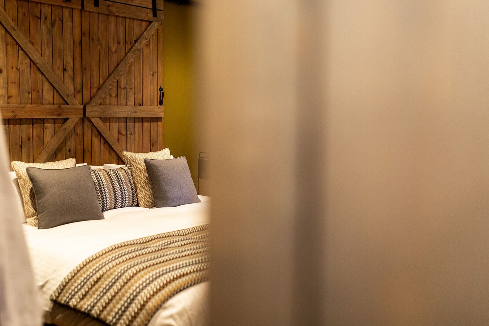 Un dormitorio con cama, almohadas y pared de madera.
