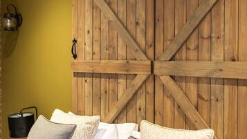 Une chambre à coucher avec une tête de lit en bois de style grange, un lit avec de nombreux oreillers et une lampe fixée au mur.