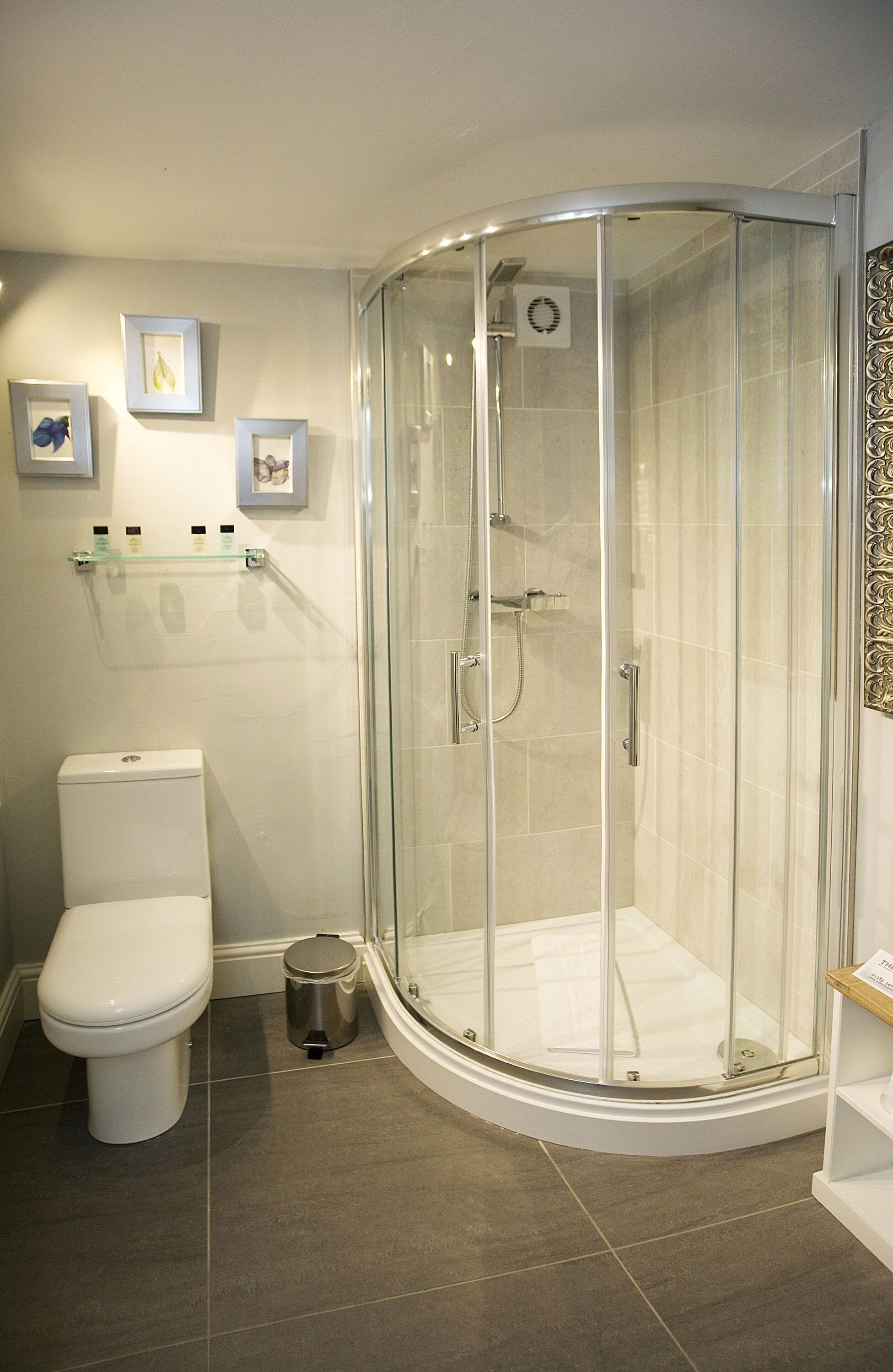Un baño moderno con ducha de vidrio, inodoro y cuadros en la pared.