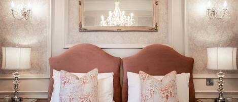 Una camera d'albergo con un letto grande, due comodini, un lampadario e uno specchio appeso al muro.