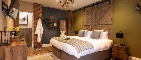 Un dormitorio con una cama grande, cabecera de madera, lámpara colgante, pared de ladrillo y puerta de madera.