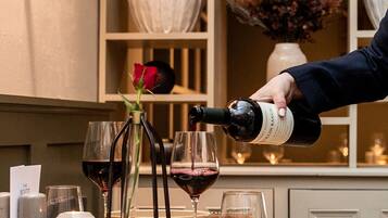 Une table à manger avec des verres à vin, une rose et une bouteille de vin dont on verse le contenu.