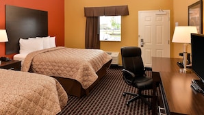 Une chambre d’hôtel avec deux lits, un bureau avec une chaise, une télévision et une fenêtre avec des rideaux.