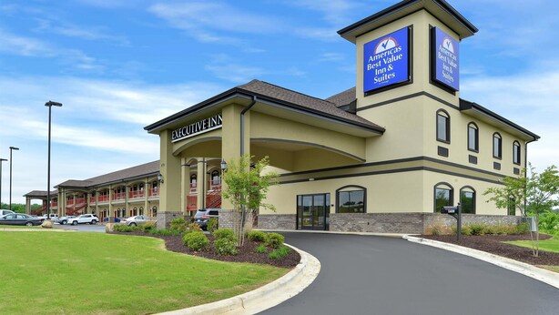 Un hôtel reconnaissable à son grand panneau « Executive Inn », à son entrée agrémentée de jardins et au ciel dégagé.