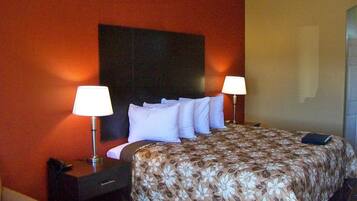 Una habitación de hotel con una cama grande, dos lámparas de noche, una mesita de noche y una silla.