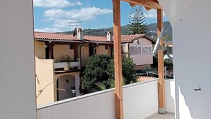 A covered balcony with a view of neighboring houses and a clear sky.