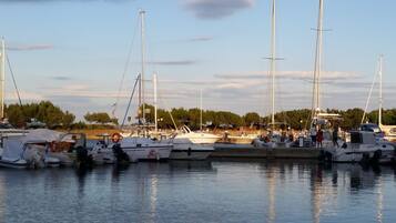 A marina with multiple boats docked, calm water, and a clear sky.