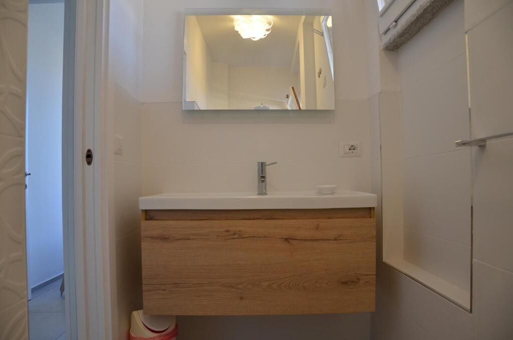 A bathroom with a white vanity, a mirror above the sink, and a shower area to the right.