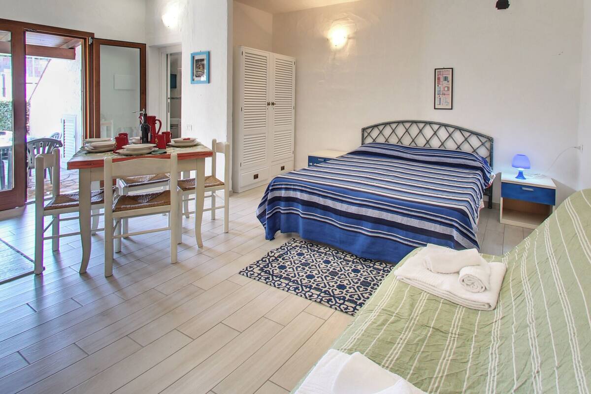 Un dormitorio con cama, escritorio, silla, sofá y una alfombra estampada.