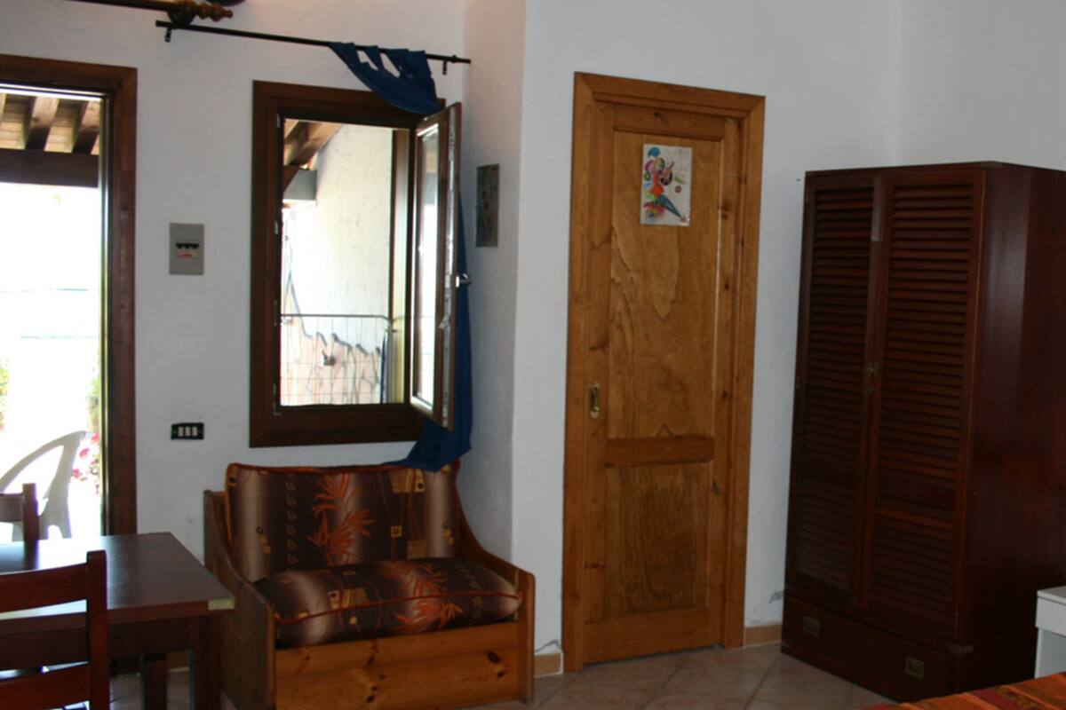Una habitación con puerta de madera, un espejo, un cartel con un pez enmarcado, una lámpara y una cama.