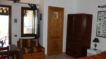 A room with a wooden door, a mirror, a framed fish poster, a lamp, and a bed.