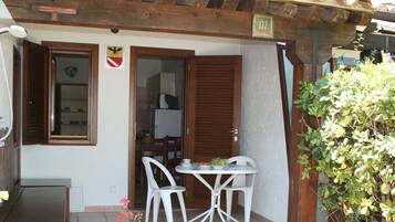 Un pequeño espacio al aire libre con comedor, una mesa, sillas, una pérgola de madera y un letrero con el número 172.