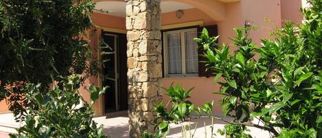 A building with a stone pillar, a door, and potted plants.