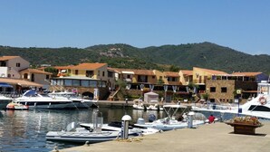 A marina with boats docked, surrounded by traditional Mediterranean-style buildings with terracotta roofs.