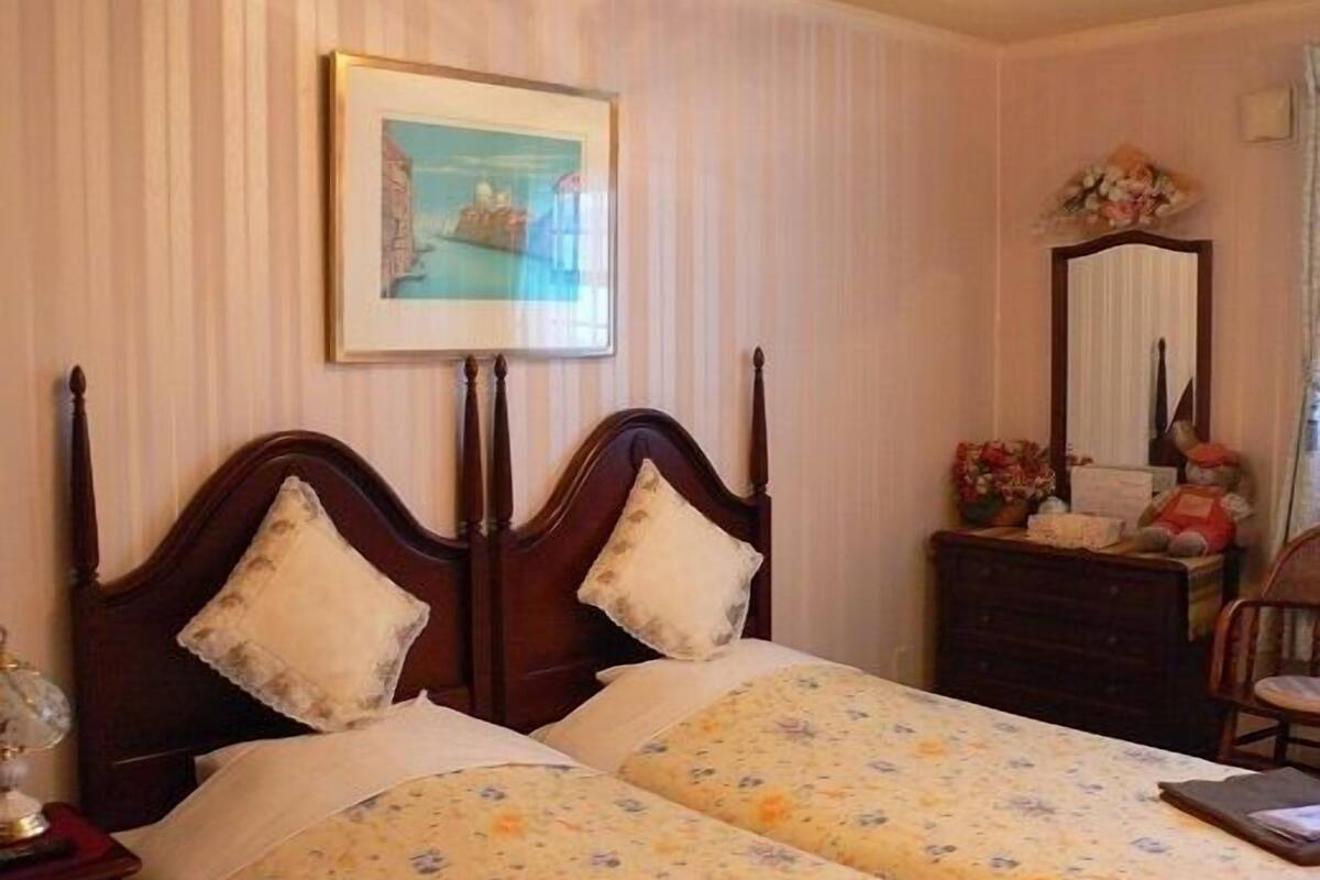 Une chambre à coucher avec un lit double, une table de chevet, une commode, un miroir et un tableau encadré au mur.