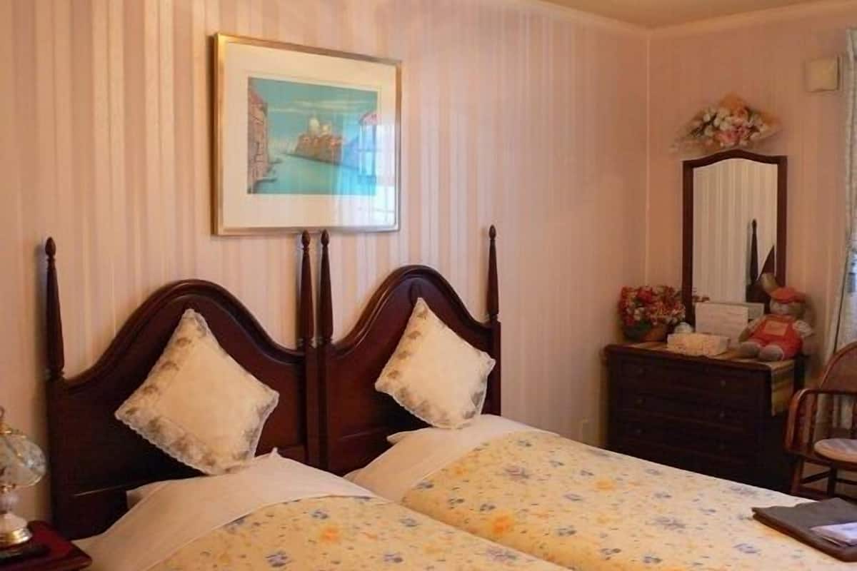 A bedroom with a double bed, a nightstand, a dresser, a mirror, and a framed picture on the wall.