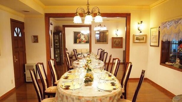 A dining room with a long table set for a meal, surrounded by chairs.