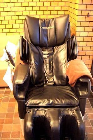 A massage chair with a backrest and armrests, positioned against a brick wall. - Yonago Town Hotel (Yonago)