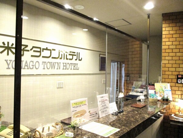 A reception area with a sign for the Youjago Town Hotel, a counter with informational brochures, a telephone, and a small plant. - Yonago Town Hotel (Yonago)