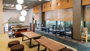 A modern interior with wooden tables and chairs, a reception area, and large windows. - Ryokan Hiromitei (Hanamaki)