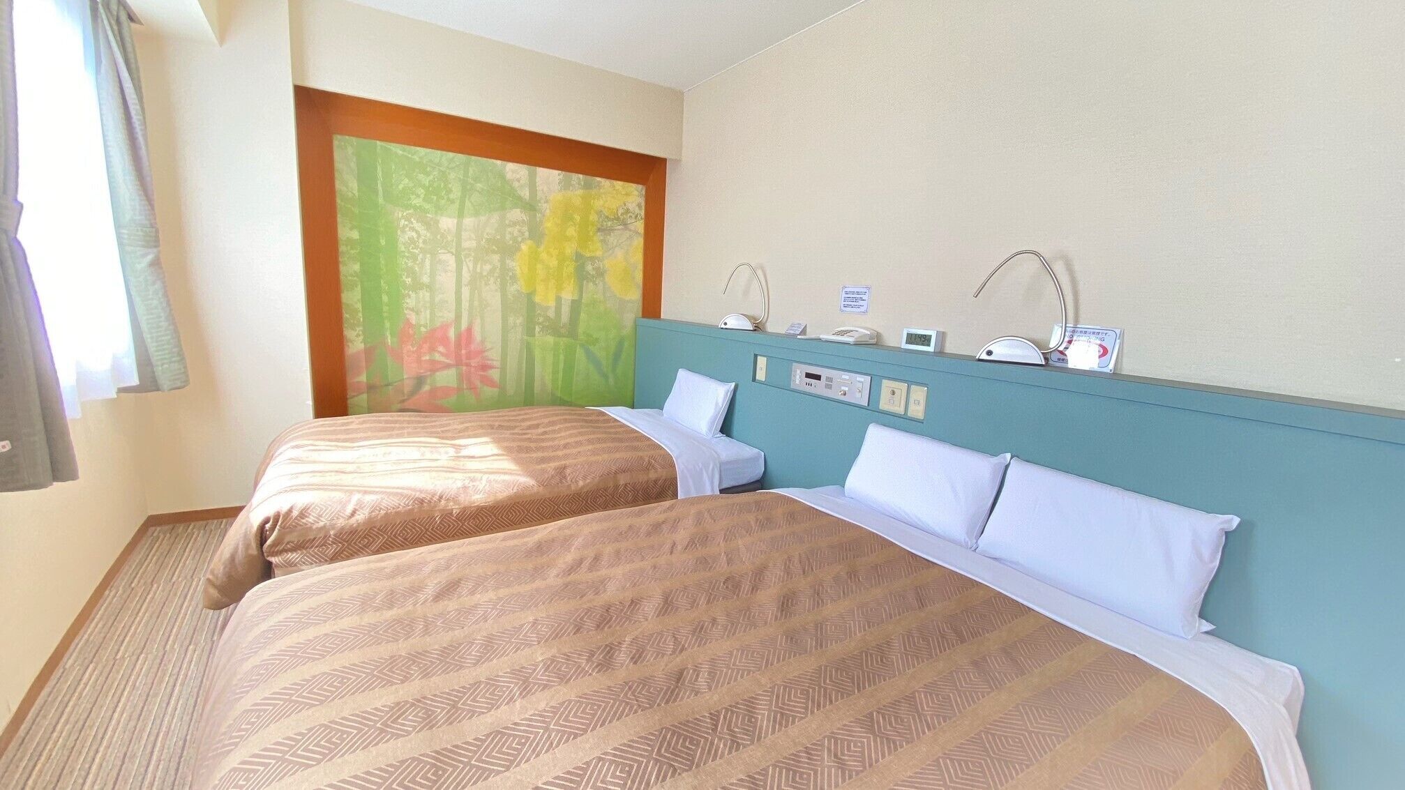 A hotel room with two beds, a painting of a forest, a bedside table with a lamp, and a clock.