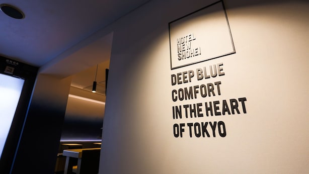 A wall with the text "HOTEL NEW SHOEI DEEP BLUE COMFORT IN THE HEART OF TOKYO". - Hotel New Shohei (Tokyo)