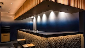 A modern kitchen with a central island, built-in bar, and a unique textured backsplash. - Hotel New Shohei (Tokyo)
