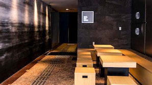 A modern hotel lobby with a long reception desk, a seating area with benches, and a wall-mounted sign. - Hotel New Shohei (Tokyo)