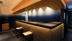 A modern kitchen with a central island, two bar stools, and a patterned backsplash. - Hotel New Shohei (Tokyo)