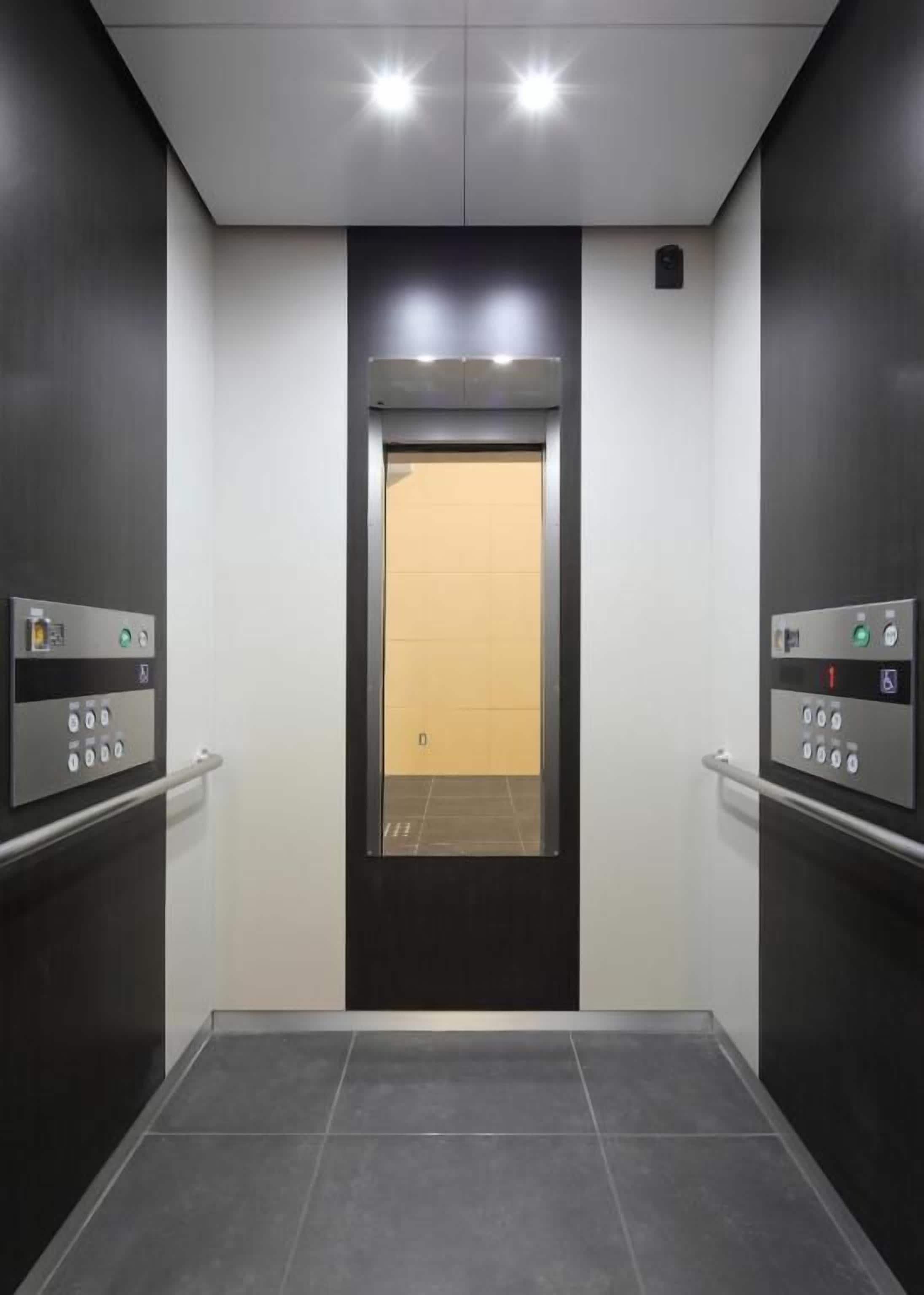 Un ascensor con un panel de control a cada lado, una puerta con un tablero luminoso y un suelo de baldosas.