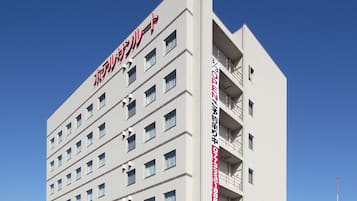 A multi-story hotel with a modern design, featuring a prominent red sign on the top.