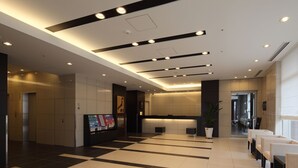 A modern hotel lobby with a checkered floor, a reception desk, and a seating area.