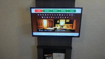 Uma televisão exibe uma imagem de um quarto de hotel com uma cama, uma mesa de cabeceira e uma luminária.
