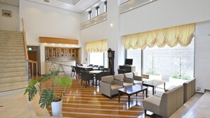 A spacious living area with a wooden floor, a dining set, sofas, and a television.