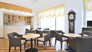 Un hall de hotel con mobiliario de mimbre, un reloj y una zona de bar.