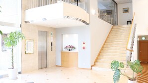 En moderne hotellobby med reception, trappe og plantekasser.