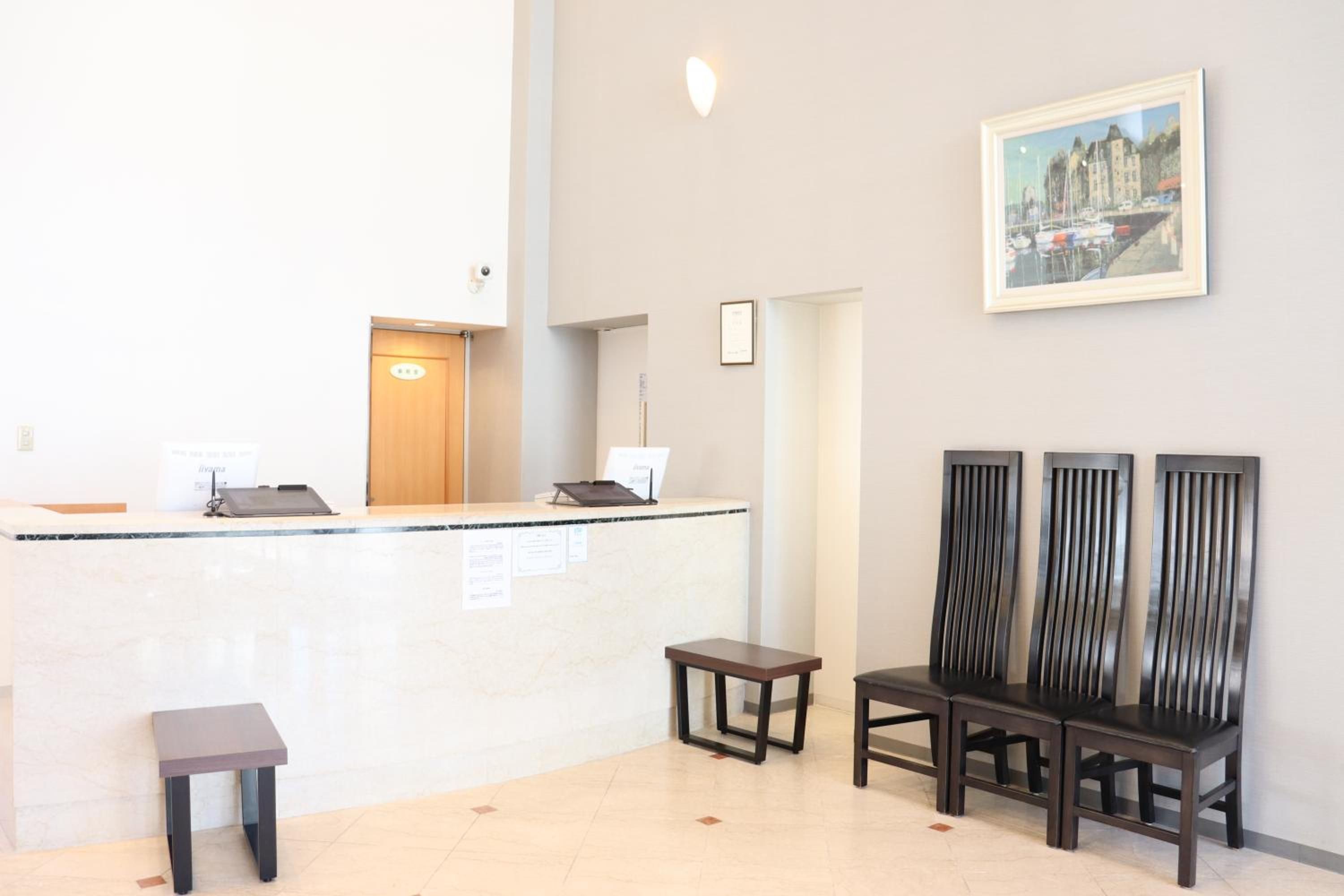 A reception area with a counter, a small table, and three chairs.