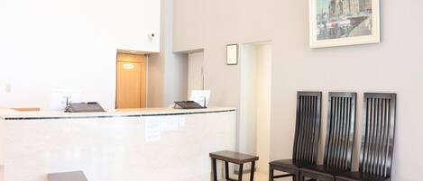 A reception area with a counter, a small table, and three chairs.