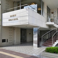 Exterior del HOTEL MABARI URBAN con un diseño moderno, que incluye una entrada destacada, fachada de vidrio y una escalera que lleva a los niveles superiores.
