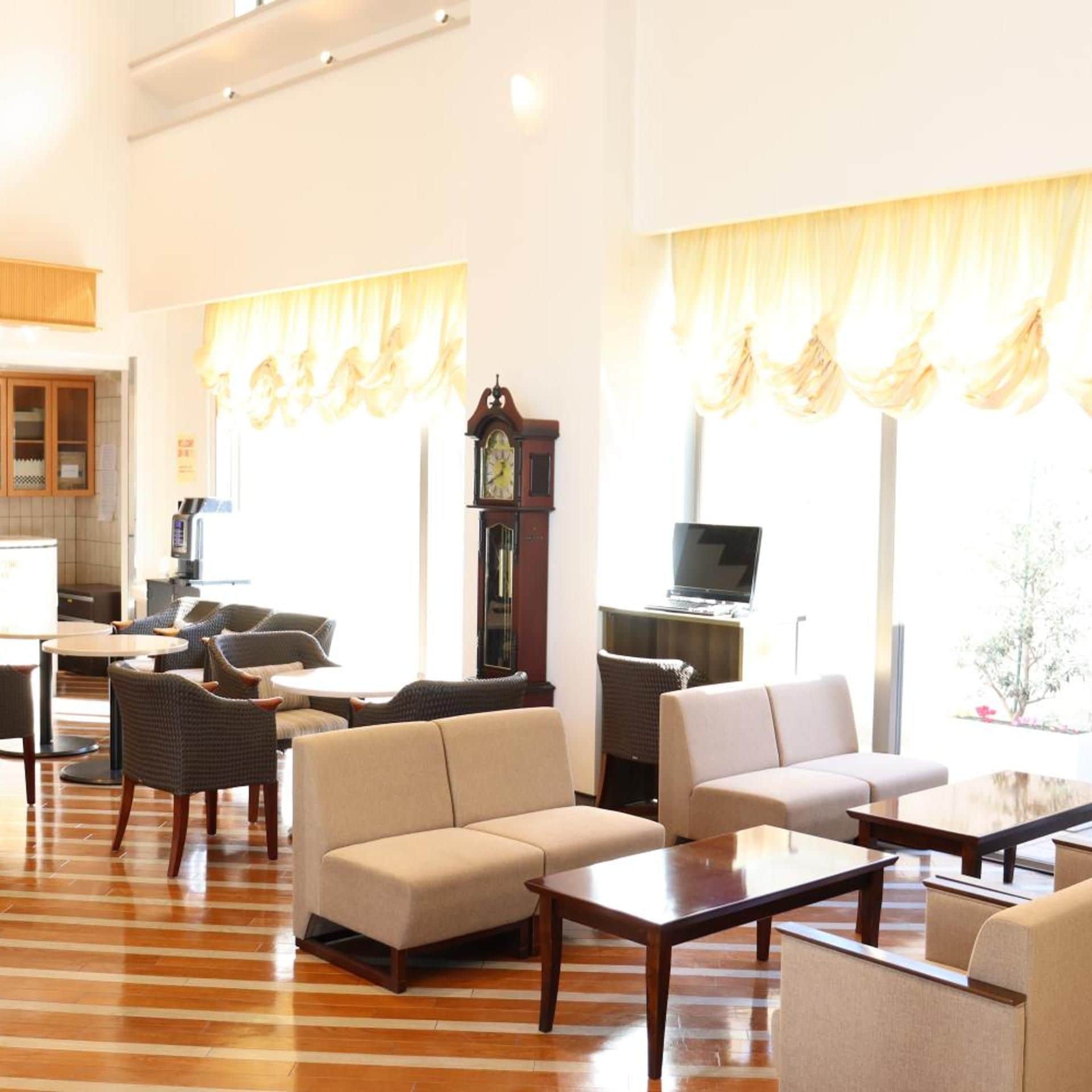 A spacious living area with a sofa set, a coffee table, and a television on a stand.
